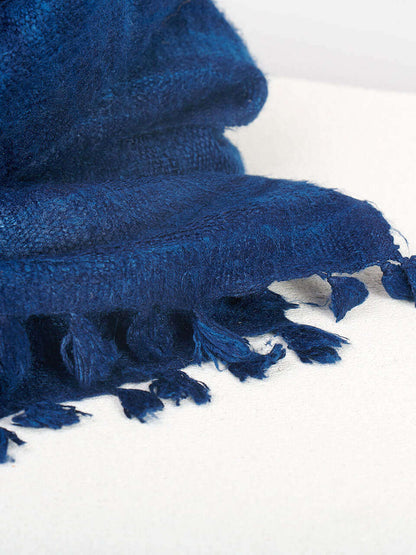 A blue Eri silk shawl spread out on a surface, highlighting its soft texture and natural color.