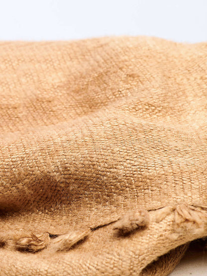 A beige Eri silk shawl spread out on a surface, highlighting its soft texture and natural color.