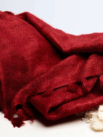 A red Eri silk shawl spread out on a surface, highlighting its soft texture and natural color.