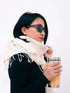A woman wearing a stylish scarf and sunglasses, exuding elegance and confidence in a sunny outdoor setting.