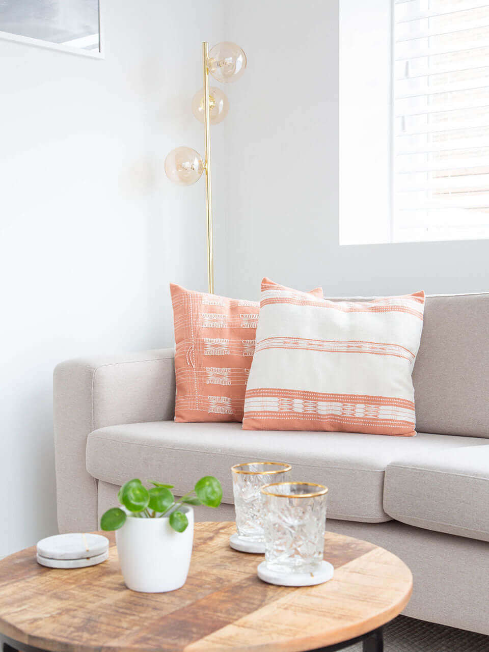 A cozy living room featuring a comfortable couch with pink & white pillow covers, a stylish coffee table, and a dining table for gatherings.