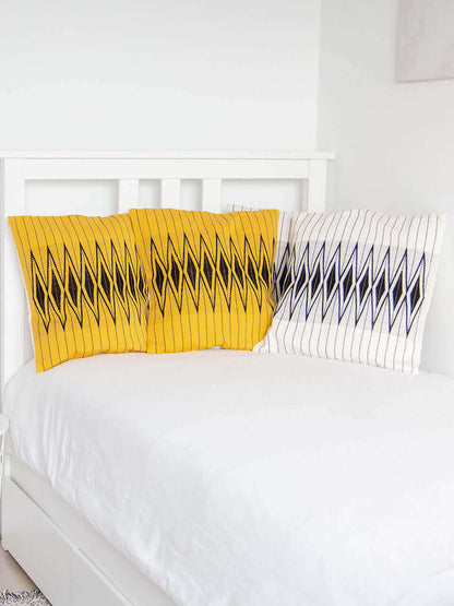 A white bed adorned with yellow and white pillow covers with beautiful black patterns, creating a vibrant and inviting atmosphere.