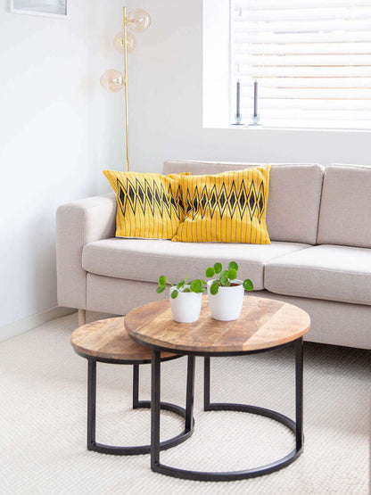 A cozy living room featuring a comfortable couch with yellow pillow cover with black pattern, a stylish coffee table, and a dining table for gatherings.