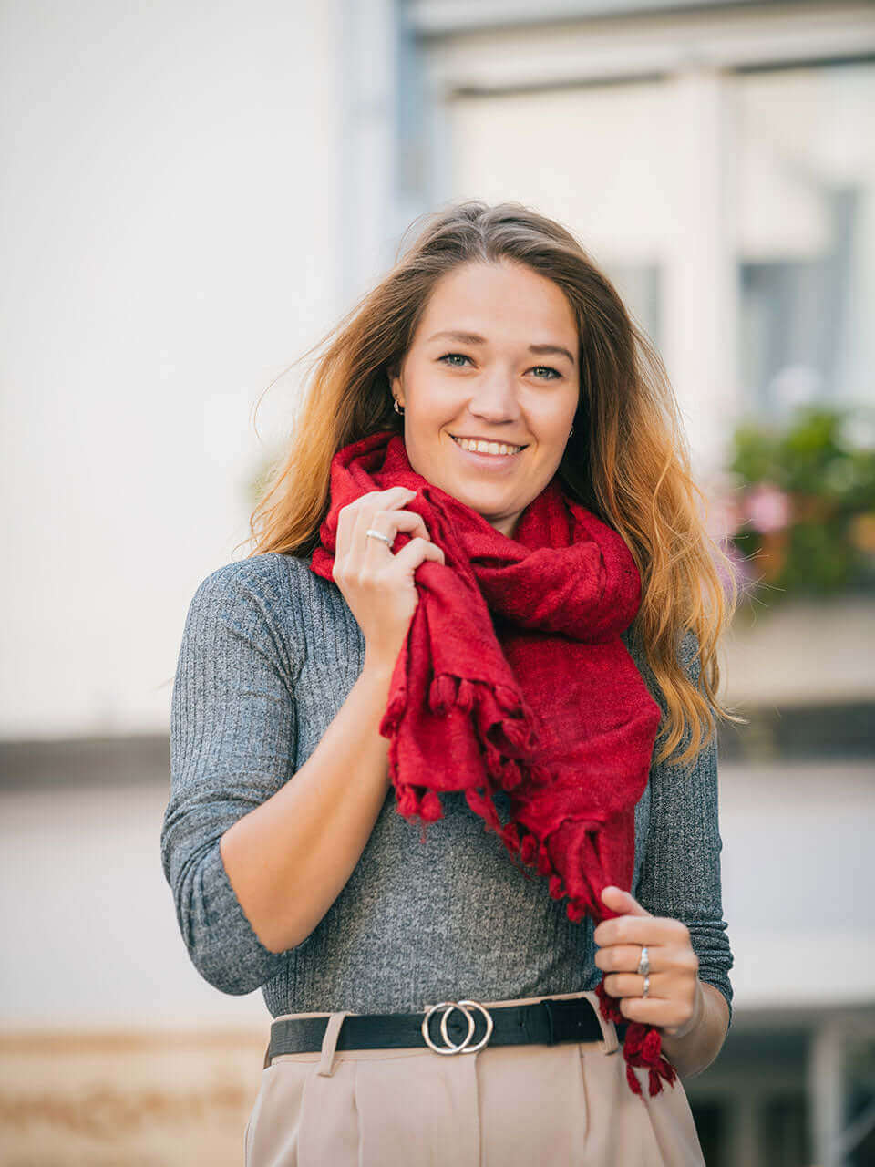 A woman draped in a soft, elegant red Eri silk shawl, showcasing its smooth texture and natural color.