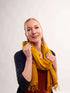 A woman elegantly draped in a vibrant yellow scarf, exuding warmth and style.